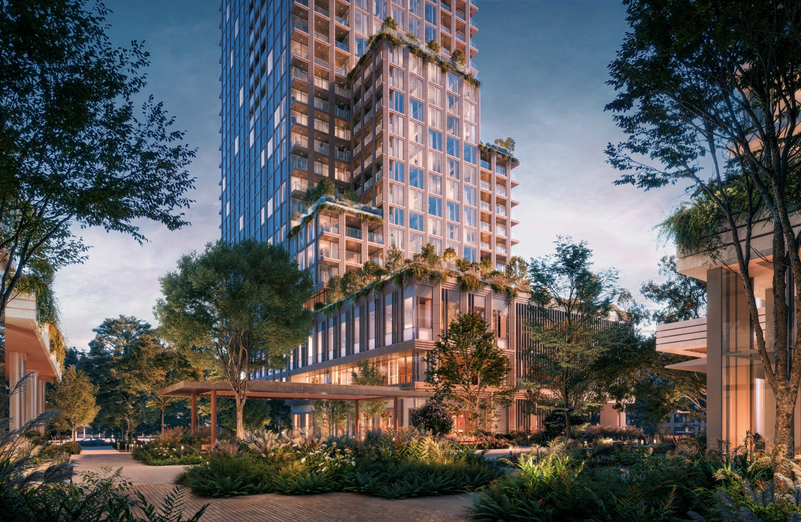 Luxury hotel tower at dusk with landscaped courtyard and illuminated entrance